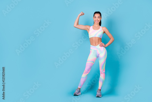 Photo of lady bodybuilder trainer demonstrate triceps wear rainbow print top leggings pants isolated blue color background