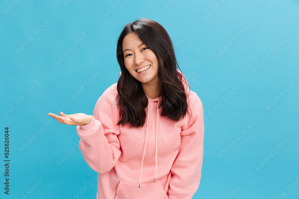 Excited happy Asian student young lady in pink hoodie sweatshirt raise palms up posing isolated on over blue studio background. The best offer for ad. People Emotions for Everyday concept Excited happy Asian student young lady in pink hoodie sweatshirt raise palms up posing isolated on over blue studio background. The best offer for ad. People Emotions for Everyday concept