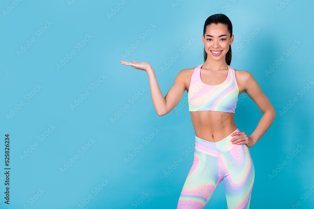 Photo of japanese lady coach demonstrate options wear rainbow print top leggings isolated blue color background Photo of japanese lady coach demonstrate options wear rainbow print top leggings isolated blue color background