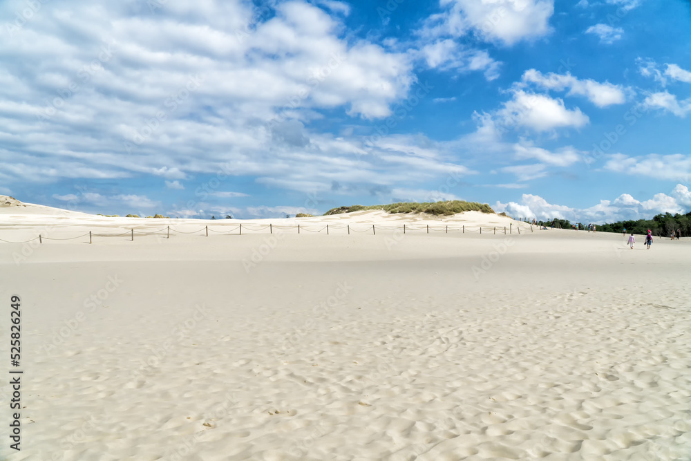 Lacka dune in Slowinski National Park in Poland. Traveling dune in sunny summer day. Sandy beach and blue sky with white clouds.