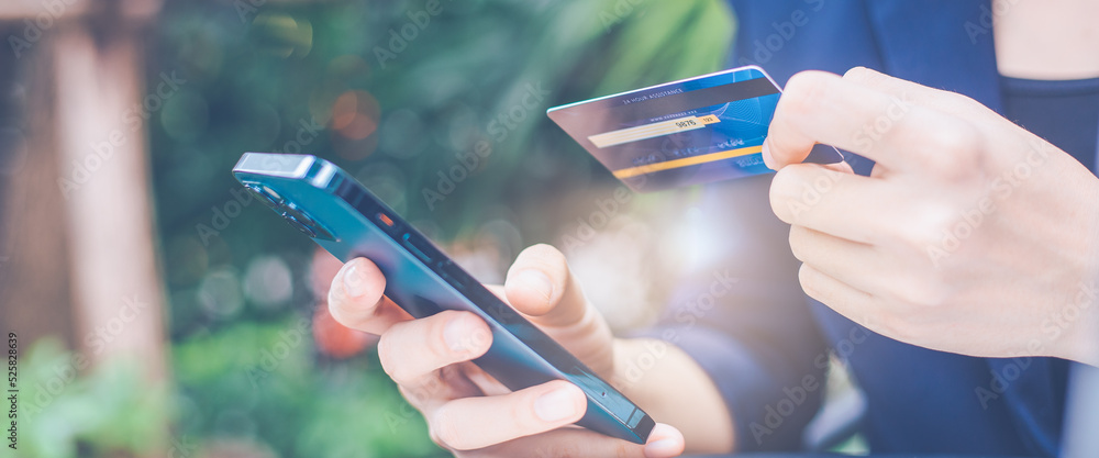 Woman hand uses a cell phone and credit card to manage online shopping.