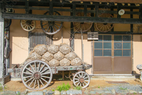 昔の日本家屋の玄関と米俵を積んだ人力車