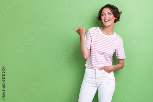 Photo of positive pretty lady wear striped outfit arm direct look empty space visit new shop low price isolated on green color background