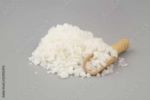 Coarse sea salt with wooden scoop on gray background close-up