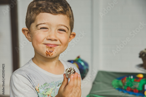menino comendo bolo de chocolate e brigadeiro em aniversário photo