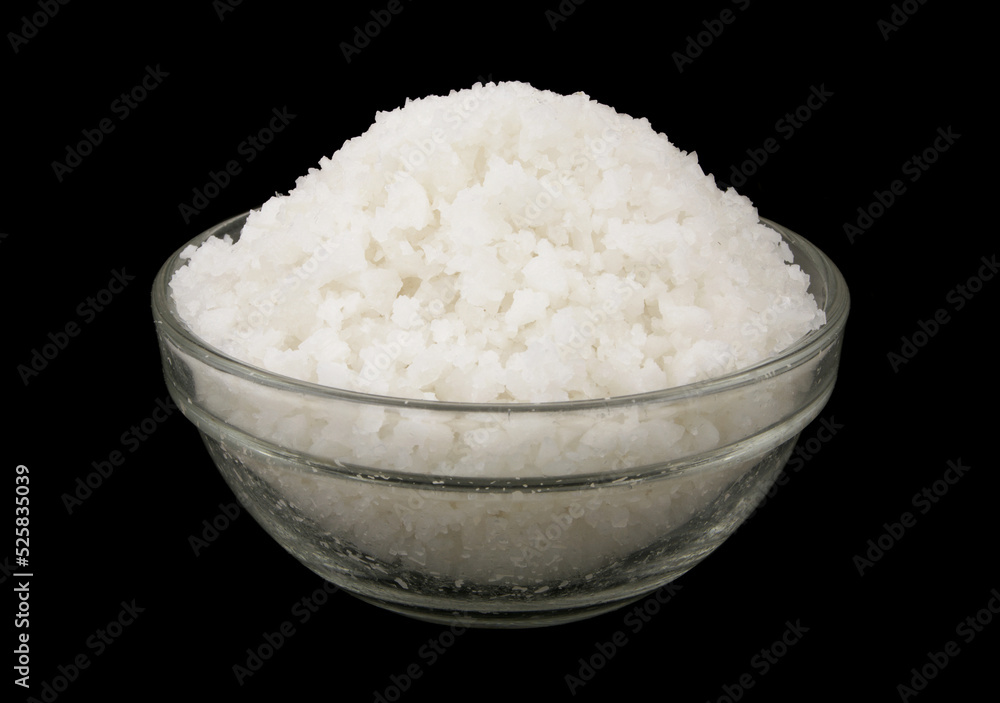 Salt in glass bowl on black background close up Salt in glass bowl on black background close up