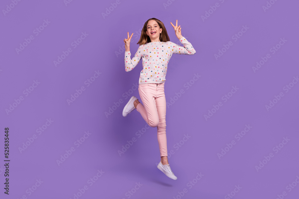 Full body portrait of excited active pupil jump arms fingers demonstrate v-sign isolated on purple color background Full body portrait of excited active pupil jump arms fingers demonstrate v-sign isolated on purple color background