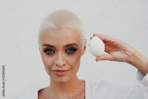 Tableau sur toile Portrait of young smiling millenial european short haired woman hold egg in hand