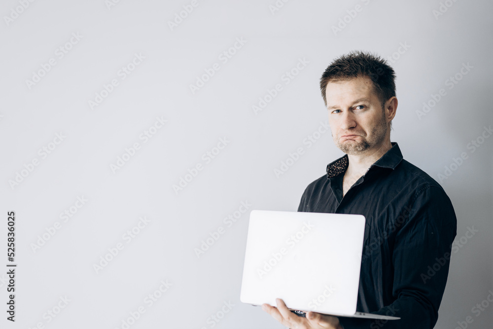 Confident IT specialist in black shirt holding laptop making faces. Confident IT specialist in black shirt holding laptop making faces.