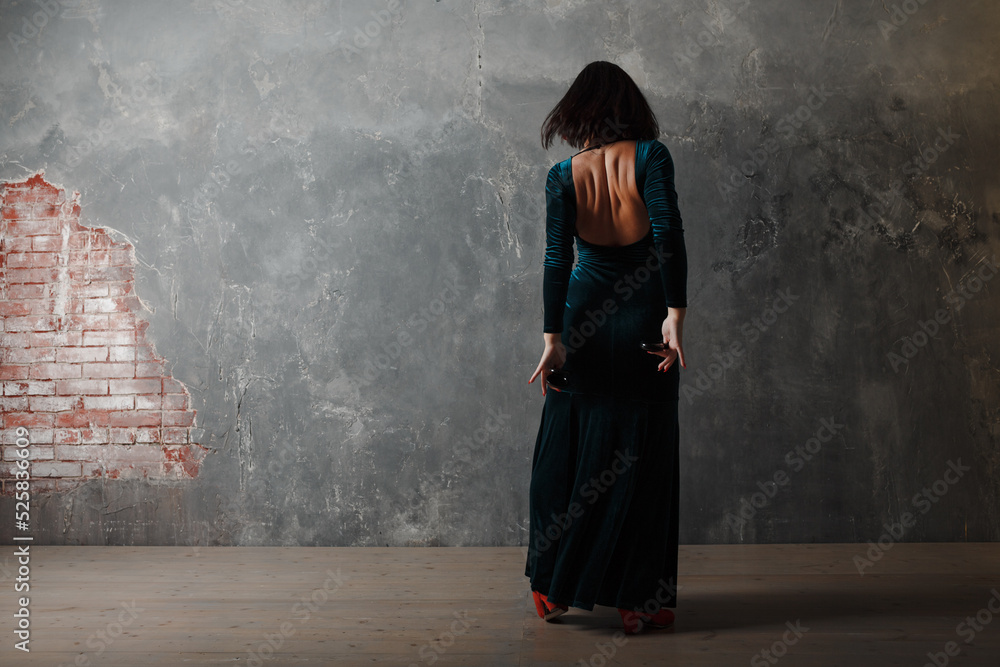 Young adult spanish woman dancing flamenco on gray vintage studio background Young adult spanish woman dancing flamenco on gray vintage studio background