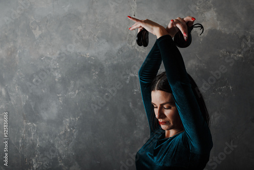 Young adult spanish woman dancing flamenco on gray vintage studio background