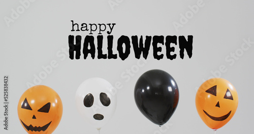 Happy halloween text banner over halloween pumpkin printed balloons against grey background