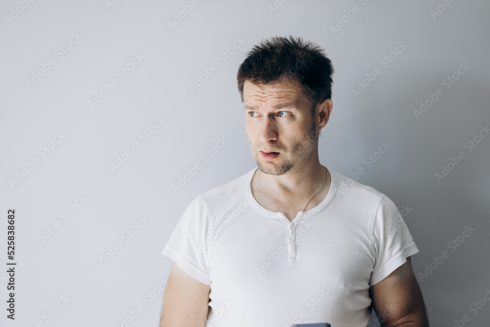 Guy programmer in a white t-shirt holds thinking Guy programmer in a white t-shirt holds thinking