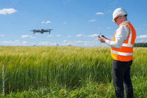Geodetic quadrocopter. Man surveyor. Quadcopter launch over field. Surveyor launches drone. Geodetic works Before construction. Surveyor in protective helmet is sent by drone. Drone surveying.