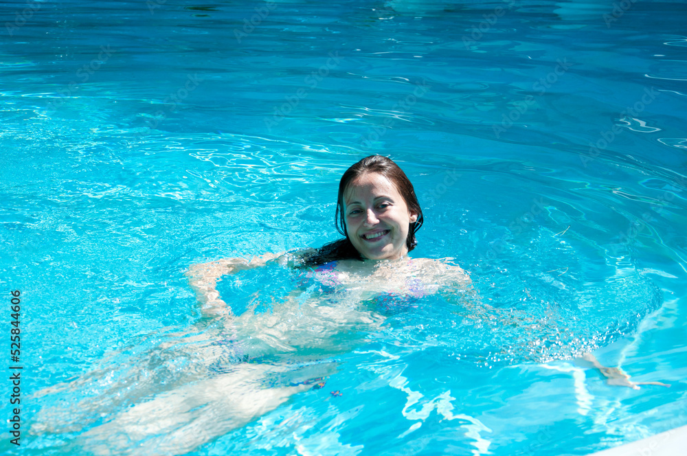 cheerful woman swimming in summer pool water on vacation