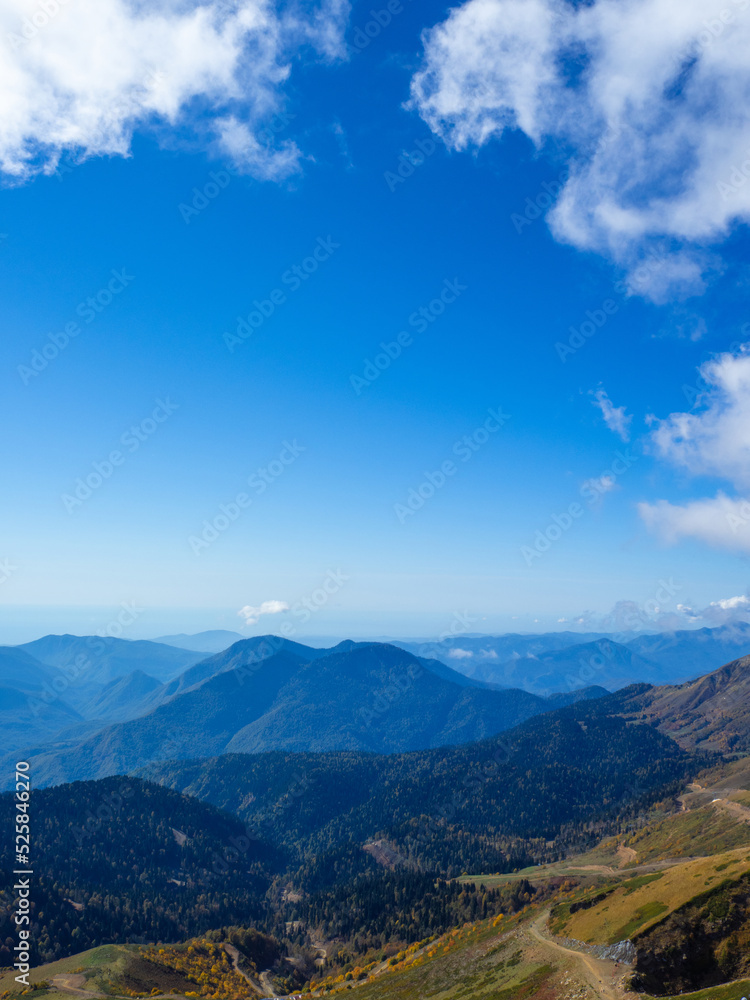 A beautiful panorama of mountains, aerial perspective, distant peaks in a blue haze, freedom and beauty of nature. Autumn view of the Caucasus mountains in Russia