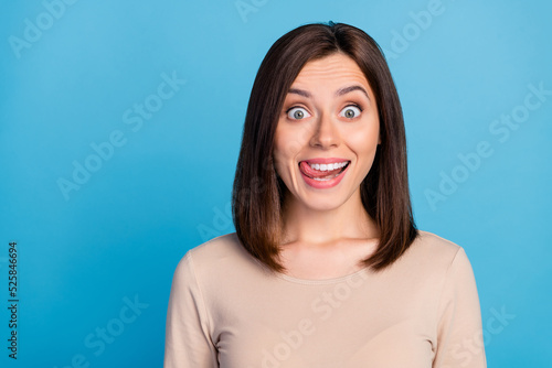 Portrait of satisfied adorable person beaming smile tongue lick teeth isolated on blue color background