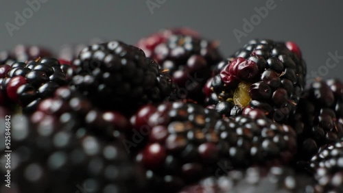 Ripe juicy blackberries swirling on a black background, slow motion.