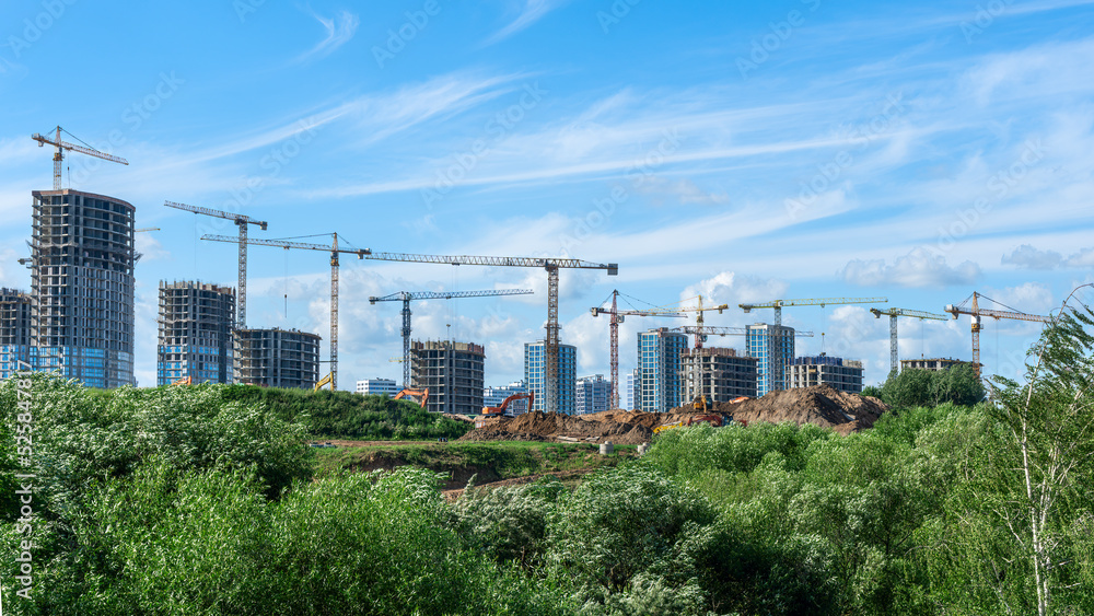 Construction of a multi-story residential buildings. A lot of construction equipment, cranes work. Construction site.