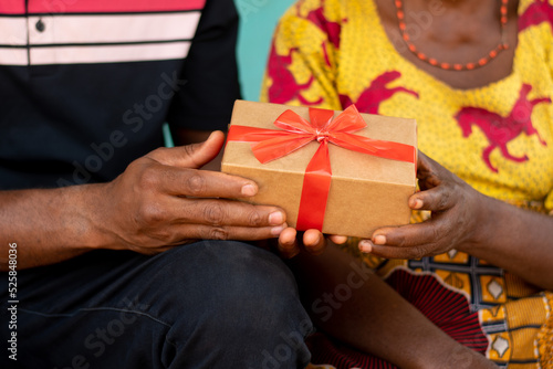 Fotografía young african man gives an old african woman a present