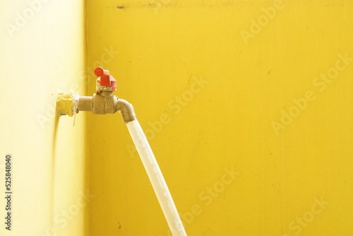 Faucet with hose on yellow wall