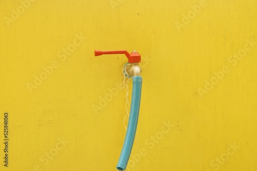 Faucet with hose on yellow wall