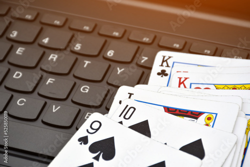 Paper cards on blank laptop keyboard, soft and selective focus, concept for playing cards online with other people at home and recreational activity.