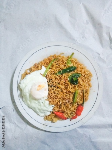 Tasty mie instant or instat noodle (Indomie Goreng) with egg and chili. Served on white plate. Isolated on white paper background,selective blurred focus photo