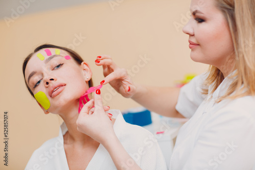 Beautiful woman applying tape lifting treatment procedure on face