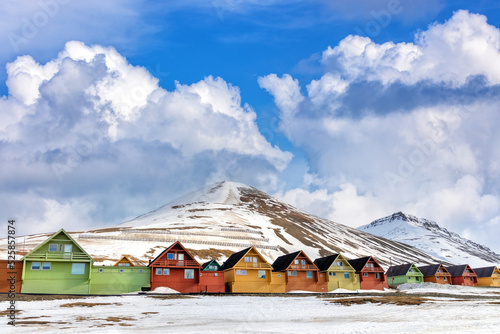 Row of colourful wooden houses in Longyearbyen, Svalbard, the most northerly town in the world. Early spring scene with snow on the mountains and the foreground photo