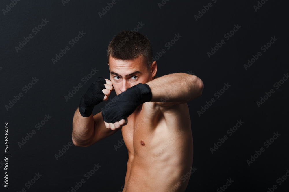 Sportsman muay thai man boxer stance at black background.