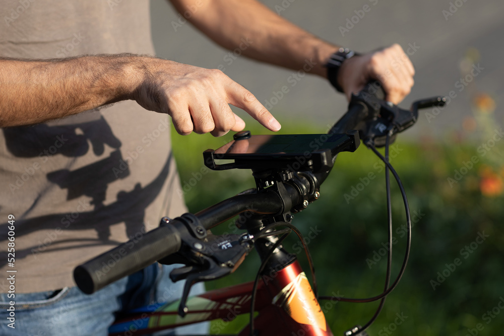 Man planning route pointing finger touch screen GPS navigation application in mobile phone on his bicycle bike Man planning route pointing finger touch screen GPS navigation application in mobile phone on his bicycle bike