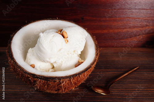 Coconut ice cream and halved coconut on wooden table (spot focus)