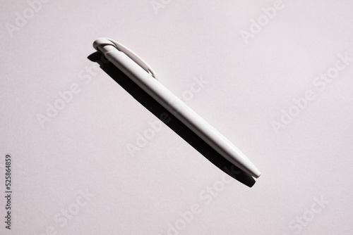 a white pen lies in the center on a gray background