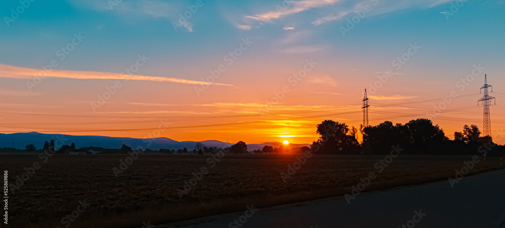 Beautiful sunset with a dramatic sky and overland high voltage lines near Tabertshausen, Bavaria, Germany Beautiful sunset with a dramatic sky and overland high voltage lines near Tabertshausen, Bavaria, Germany