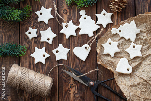 Christmas decoration made of salted dough in the shape of stars and hearts lie on a wooden table.