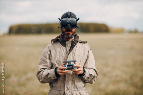 Man controlling fpv quadcopter drone for aerial photography and videography with goggles antenna remote controller.