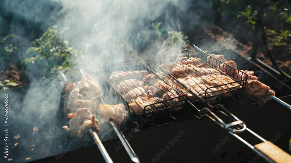 Roasting fresh juicy marinated meat in burning charcoals open fire in barbecue grill basket, cooking chicken on steel bbq grid, smoke in slow motion, sunny summer picnic in backyard, close-up. Roasting fresh juicy marinated meat in burning charcoals open fire in barbecue grill basket, cooking chicken on steel bbq grid, smoke in slow motion, sunny summer picnic in backyard, close-up.