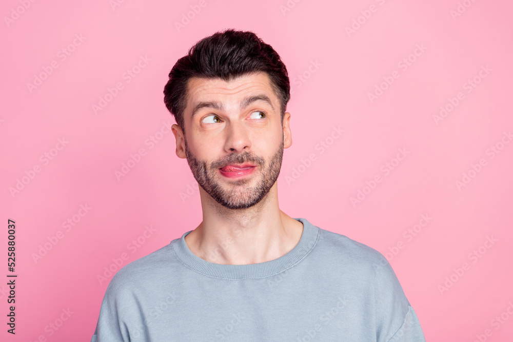 Photo of minded positive person tongue lick lip look interested empty space isolated on pink color background Photo of minded positive person tongue lick lip look interested empty space isolated on pink color background