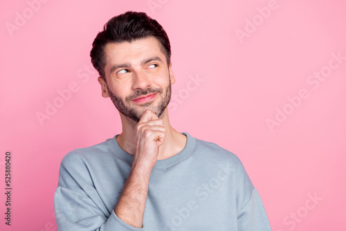 Portrait of creative positive man arm touch chin look interested empty space isolated on pink color background