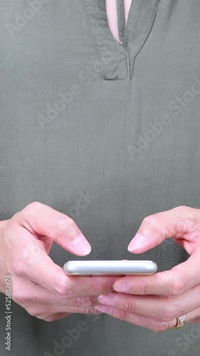 Closeup of a woman's hands using a Smartphone to text or chat with friends, with copy space for your custom text, or graphics. Vertical video for seamless mobile viewing