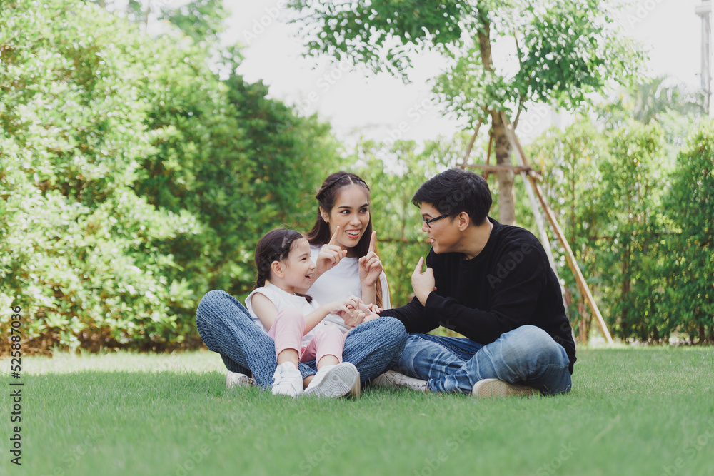 Asian Family with a child playing on a lawn, Family sitting on the grass with her happy and adorable little daughter, enjoyment relaxing recreational concept. Asian Family with a child playing on a lawn, Family sitting on the grass with her happy and adorable little daughter, enjoyment relaxing recreational concept.