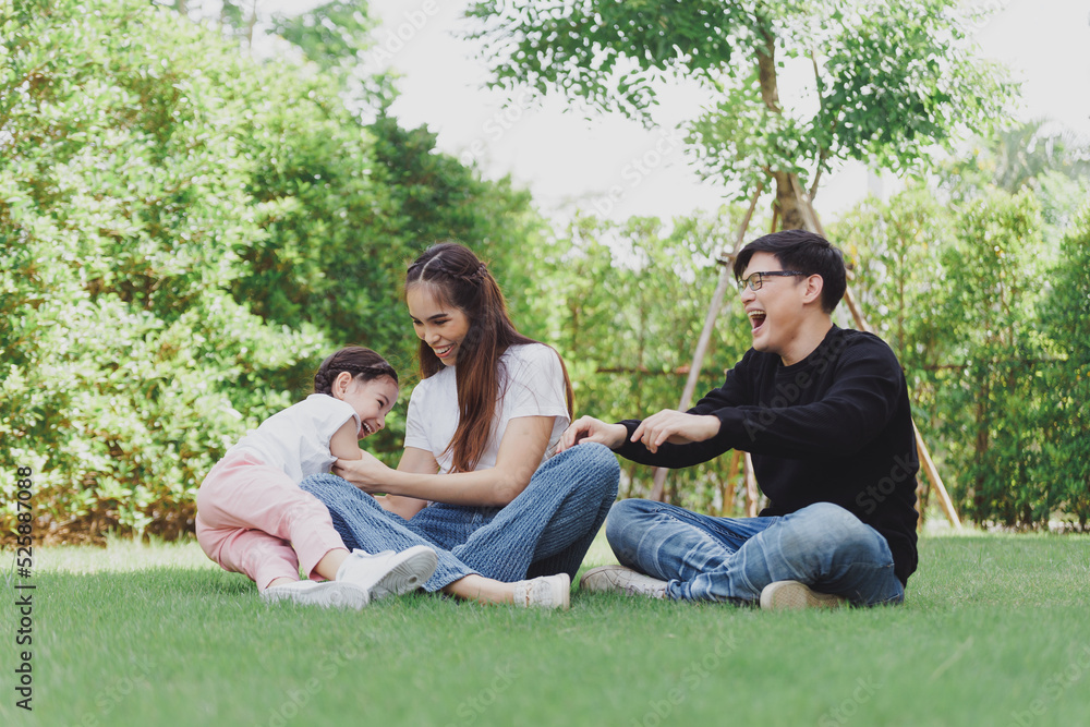 Asian Family with a child playing on a lawn, Family sitting on the grass with her happy and adorable little daughter, enjoyment relaxing recreational concept. Asian Family with a child playing on a lawn, Family sitting on the grass with her happy and adorable little daughter, enjoyment relaxing recreational concept.