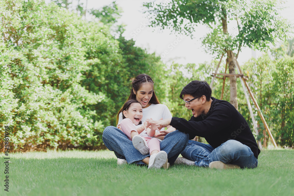 Asian Family with a child playing on a lawn, Family sitting on the grass with her happy and adorable little daughter, enjoyment relaxing recreational concept. Asian Family with a child playing on a lawn, Family sitting on the grass with her happy and adorable little daughter, enjoyment relaxing recreational concept.