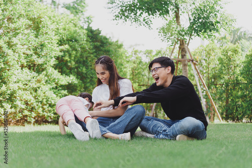 Asian Family with a child playing on a lawn, Family sitting on the grass with her happy and adorable little daughter, enjoyment relaxing recreational concept. © nikomsolftwaer