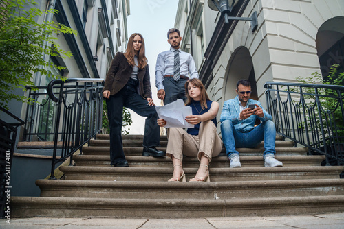 Shot of four professional businesspeople analyzing documents outdoors in daytime.
