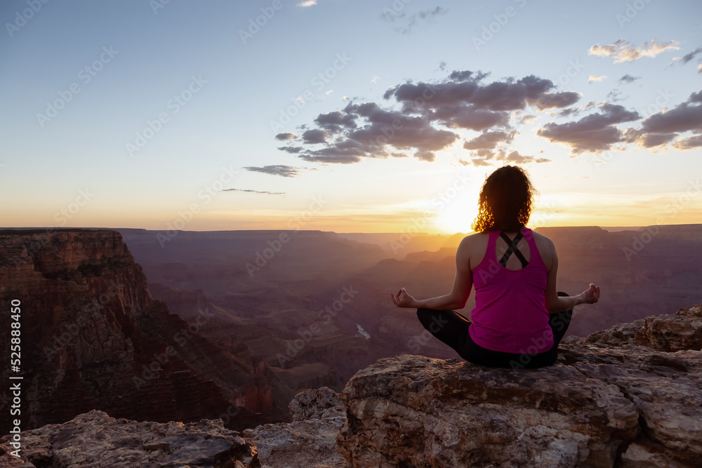 Adventurous Traveler woman doing meditation on Desert Rocky Mountain American Landscape. Cloudy Sunny Sky. Grand Canyon National Park, Arizona, United States. Adventure Travel