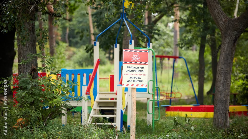 Horenka, Ukraine - August 25, 2022: The consequences of russian invasion in Kyiv region near Gostomel. Playground and sign. Words on the sign: Beware Mines