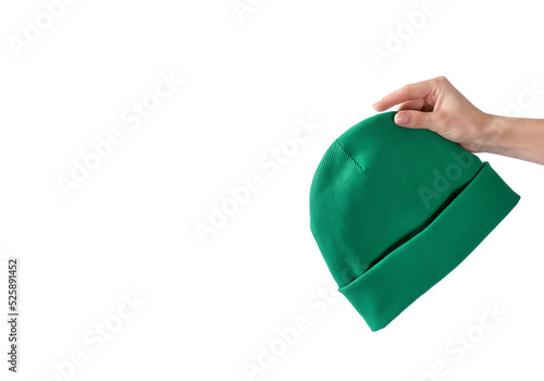 Green beanie hat in a girl's hand on a white background. Autumn headdress unisex. Copy space
