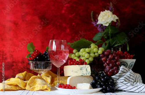 Still life with cheese and wine on a table. Delicious French cheese and glass of a pink wine. Colorful photo of tasty delicatessen.  